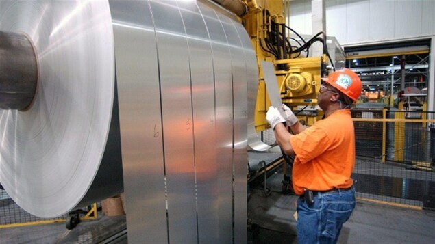 Un travailleur inspecte une feuille d'aluminium.