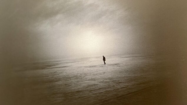 Une photographie de la silhouette d'un homme qui marche seul dans le désert. 
