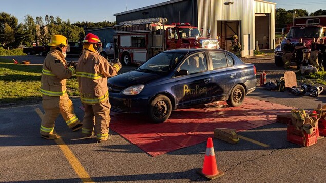 Deux pompiers s'approchent d'un véhicule accidenté Deux pompiers s'approchent d'un véhicule accidenté