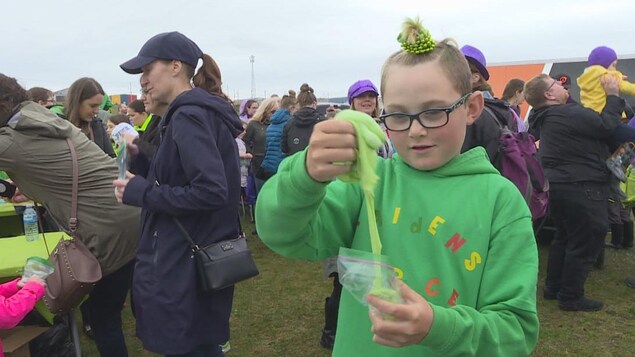 Un enfant manipule de la glu verte et porte un chandail vert assorti.