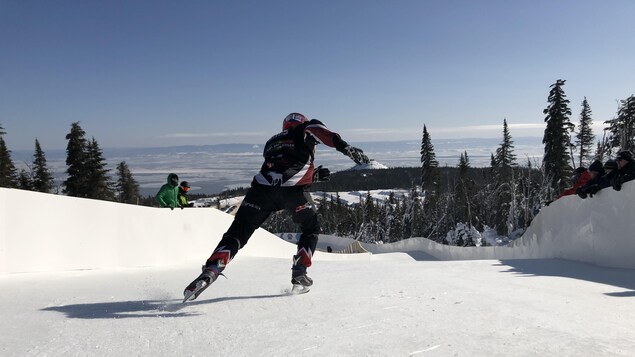 Un homme donnant un coup de patin dans un parcours de Ice Cross avec la vue sur le fleuve.