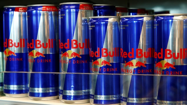 Des cannettes de Red Bull sont alignées sur une étagère commerciale.