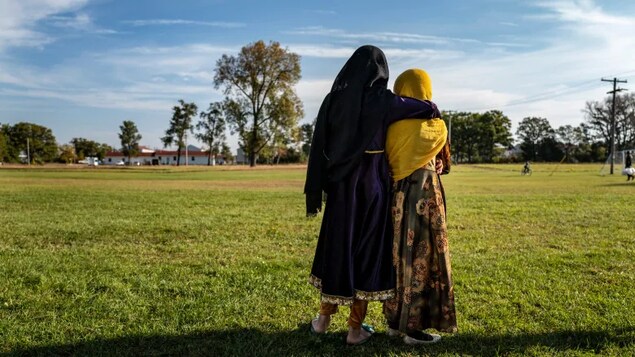 Afghan refugee girls watch a soccer game from a distance at the Fort McCoy army base in Fort McCoy, Wisc., on Sept. 30. Ordinary Americans and the country's airlines are combining to donate miles and cash to help Afghan refugees resettle in the United States.