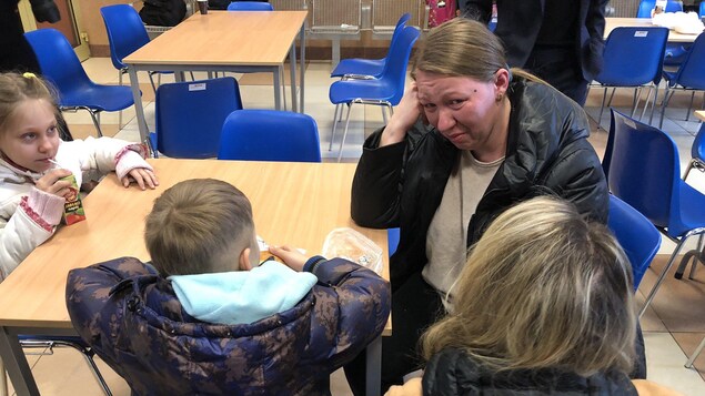 Mélanie Joly discutant avec une femme en pleurs accompagnée de ses deux enfants.