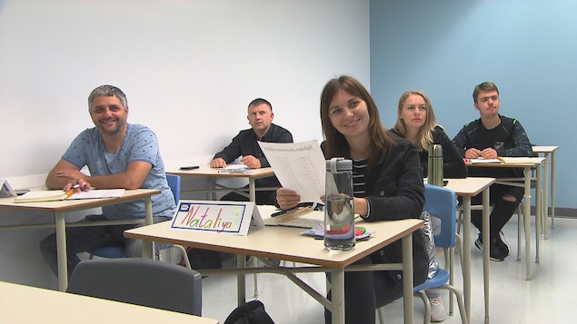 Des étudiants sont assis à leur pupitre dans une salle de classe. 