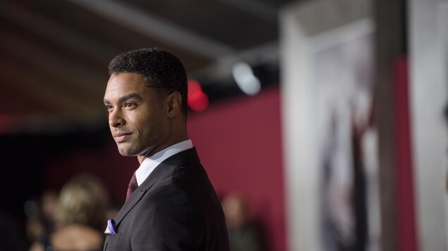 Un homme en complet prend la pose sur le tapis rouge.