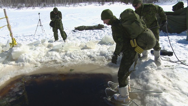 Un militaire se jette à l'eau avec des raquettes aux pieds et un sac sur son dos. Un militaire se jette à l'eau avec des raquettes aux pieds et un sac sur son dos.