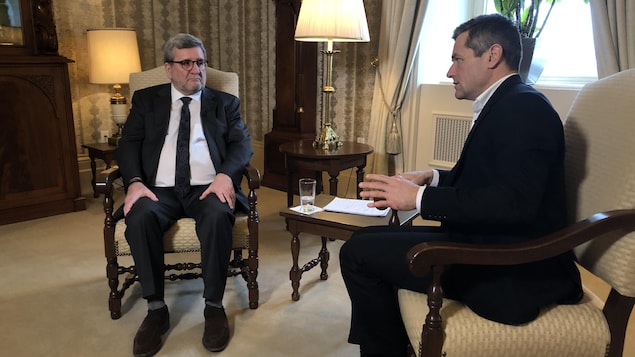 Régis Labeaume à gauche assis sur une chaise, Bruno Savard à droite, lui ausssi assis.