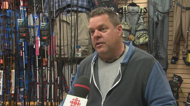 Un homme accorde une entrevue à Radio-Canada dans un magasin d'articles de pêche.