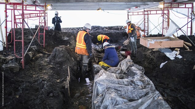 Des conservateurs tentent d'extirper les morceaux du rempart palissadé de Beaucours à Québec de la glaise avant la période de gel Des conservateurs tentent d'extirper les morceaux du rempart palissadé de Beaucours à Québec de la glaise avant la période de gel