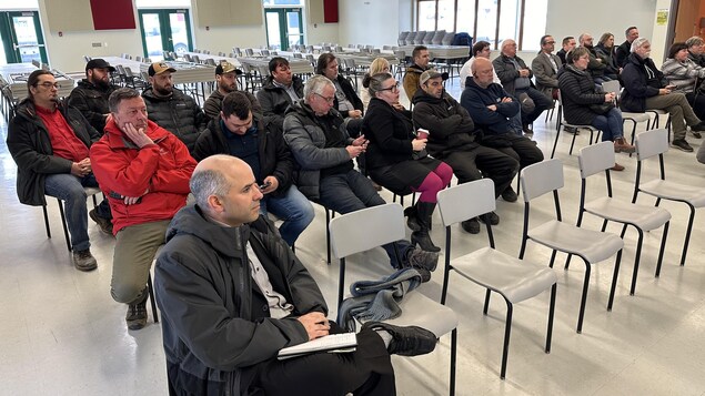 Des gens dans une salle qui écoutent.
