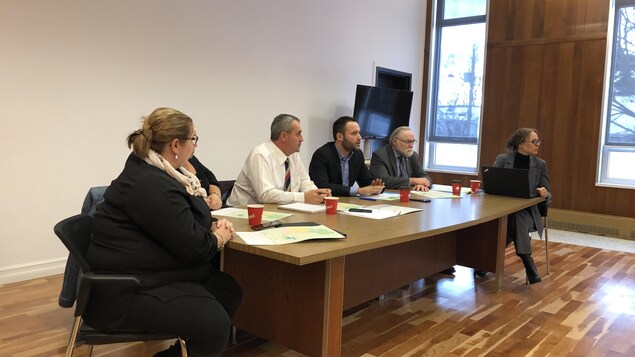 Trois femmes et trois homme assis autour d'une table dans une salle de conférence.