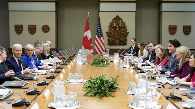 Le cortège ministériel canadien à droite fait face à ses homologues américains à gauche, tous assis à une longue table.