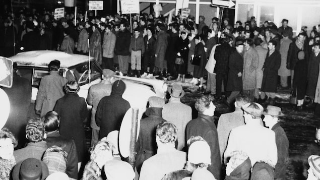 Lors de la grève des réalisateurs de Radio-Canada en 1958-1959, à l'extérieur à
5h30 PM à proximité de l'édifice de Radio-Canada, une voiture circule sur une
rue où une foule compacte est massée de chaque côté sur les trottoirs. Parmi les gens présents, des grévistes avec des pancartes. Lors de la grève des réalisateurs de Radio-Canada en 1958-1959, à l'extérieur à
5h30 PM à proximité de l'édifice de Radio-Canada, une voiture circule sur une
rue où une foule compacte est massée de chaque côté sur les trottoirs. Parmi les gens présents, des grévistes avec des pancartes.