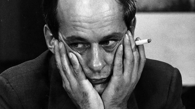 L'animateur René Lévesque, l'air pensif, son visage appuyé et encerclé de ses mains, une cigarette entre les doigts.