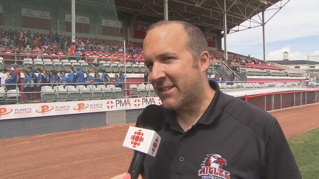 Sur le terrain de baseball, il répond aux questions de la journaliste.