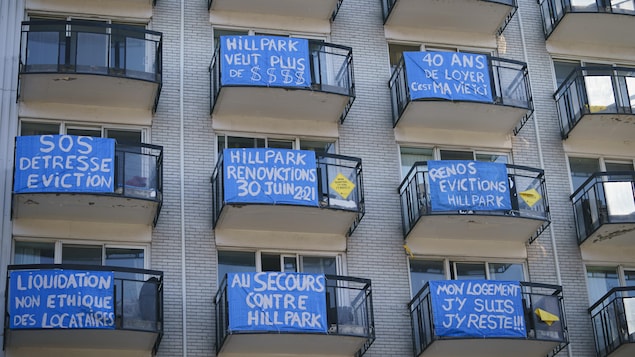Des pancartes de contestation installées sur des balcons de logements d'un immeuble.
