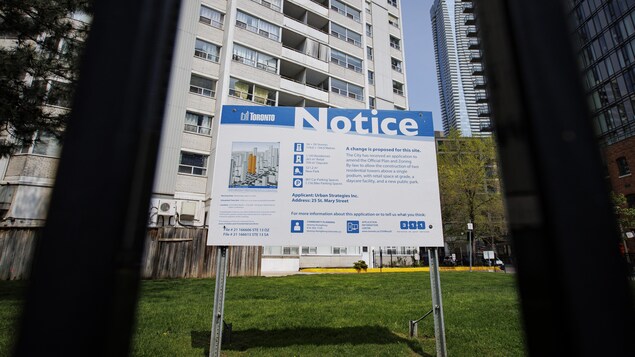 Une grande affiche avec le mot Avis est placée devant un immeuble d'appartements.