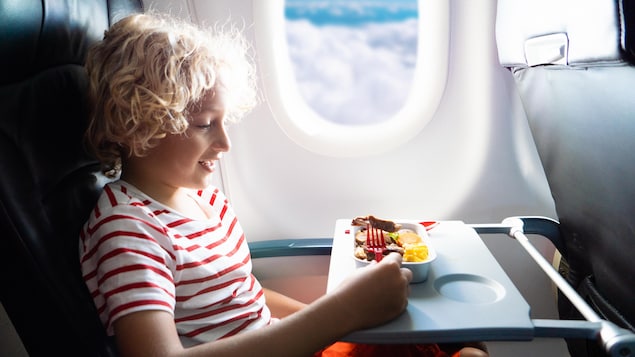 Un enfant devant un repas dans son siège d'avion.