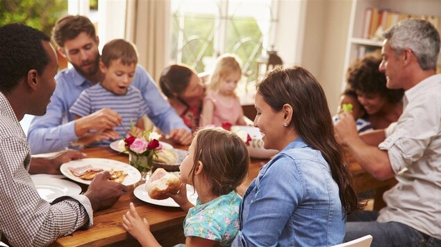 Des adultes et des enfants mangent autour d'une grande table.