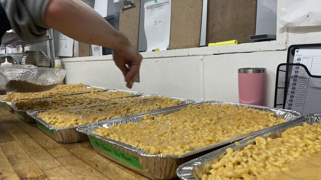 Un service de traiteur est en train de préparer du macaroni au fromage pour les athlètes.