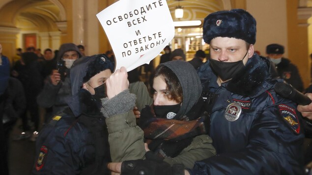 Des policiers tentent de maîtriser une manifestante.