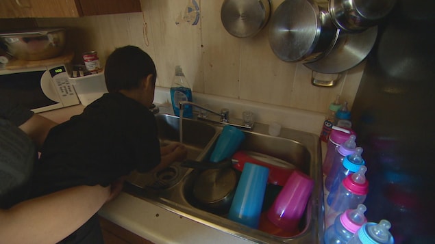 Un Autochtone de 4 ans se lave les mains dans l'évier de la cuisine. Un Autochtone de 4 ans se lave les mains dans l'évier de la cuisine.