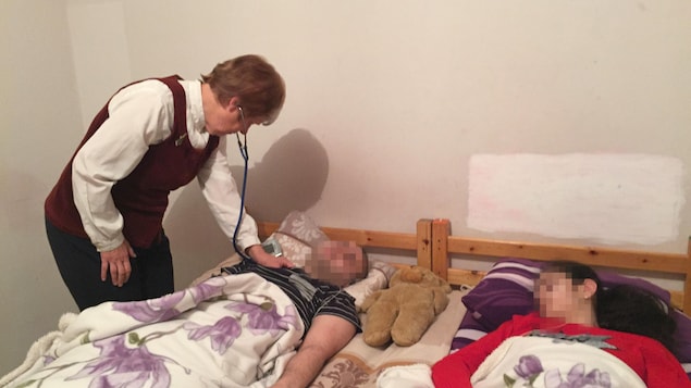 Une femme docteure examine Kostan et Miléna, deux enfants victimes du « syndrome de résignation », un mal surtout présent en Suède. Les deux enfants sont couchés dans un lit, mais ils ne dorment pas; ils sont inconscients.