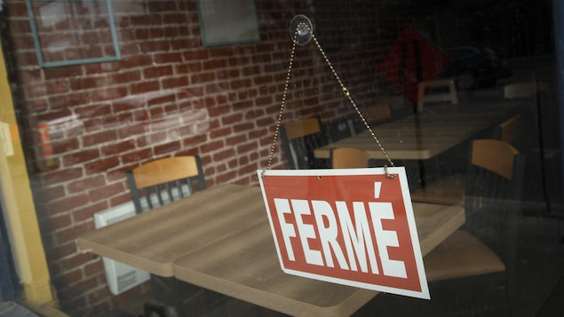 Une pancarte sur laquelle est écrit fermé accrochée à la vitre d'un restaurant.