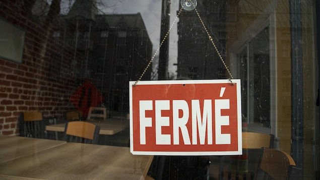 Une pancarte sur laquelle est écrit fermé accrochée à la vitre d'un restaurant.