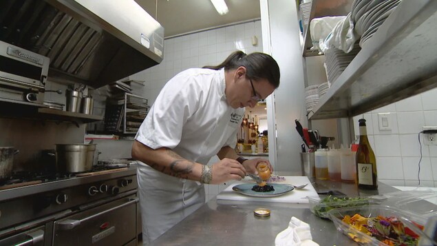 Un chef prépare une assiette dans une cuisine de restaurant.