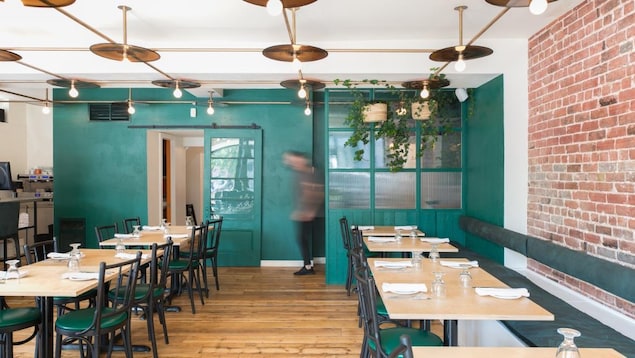 L'intérieur d'un restaurant avec des tables, des chaises, des plantes et un mur en briques. L'intérieur d'un restaurant avec des tables, des chaises, des plantes et un mur en briques.