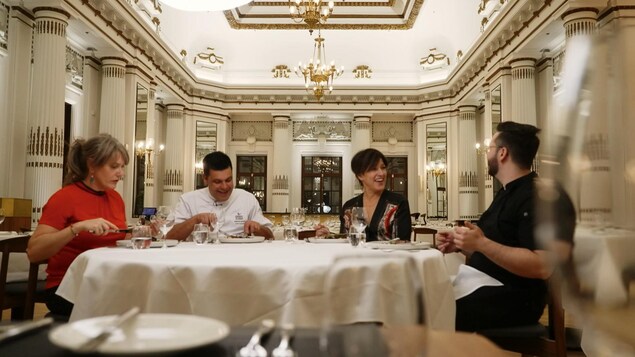 Quatre personnes à table dans la grande salle d'un restaurant. 
