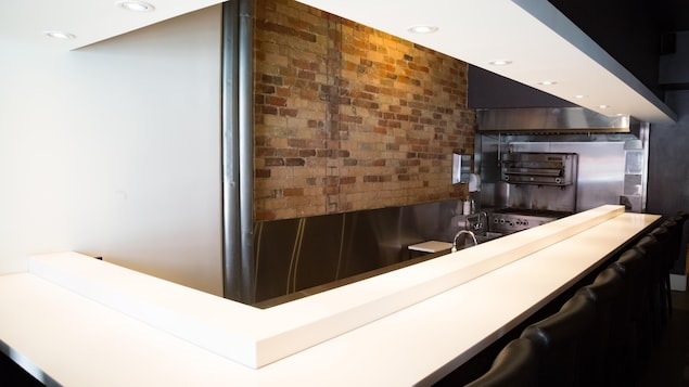 À l'Intérieur d'un restaurant. Il y a un comptoir et un mur de brique au fond. À l'Intérieur d'un restaurant. Il y a un comptoir et un mur de brique au fond.