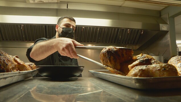Un chef portant le masque sort des poulets du four