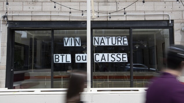 Un resto affiche une pancarte dans sa fenêtre : « Vin nature, btl ou caisse ».