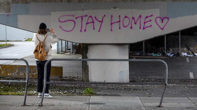 Une fille sous un pont prend en photo le graffiti.