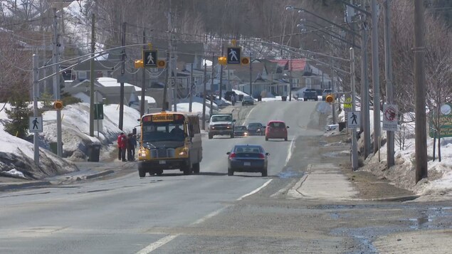 Des élèves montent à bord d'un autobus scolaire sur une route en milieu rural