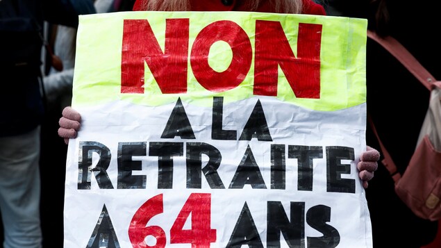 «Non à la retraite à 64 ans», peut-on lire sur cette affiche brandie par une manifestante à Paris.