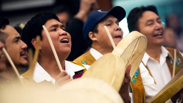 Des hommes jouent du tambour et chantent.