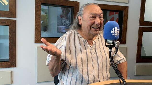 Richard Ejinagosi Kistabish lève une main pour appuyer ce qu'il raconte dans le studio de Radio-Canada à Rouyn-Noranda.