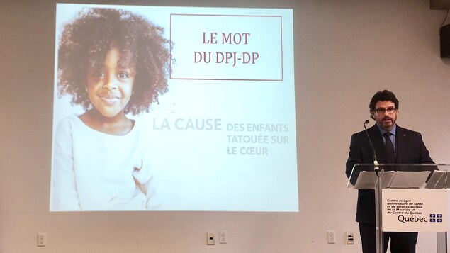 Homme sur une scène avec un écran derrière Homme sur une scène avec un écran derrière