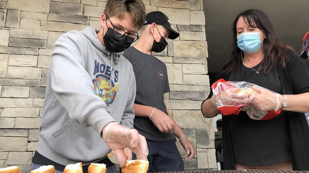 Un adolescent et une femme font griller des pains hot-dogs.