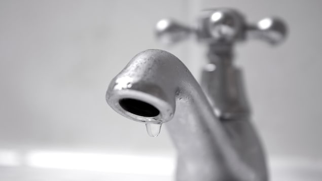 Une goutte d'eau suspendue à un robinet fermé.