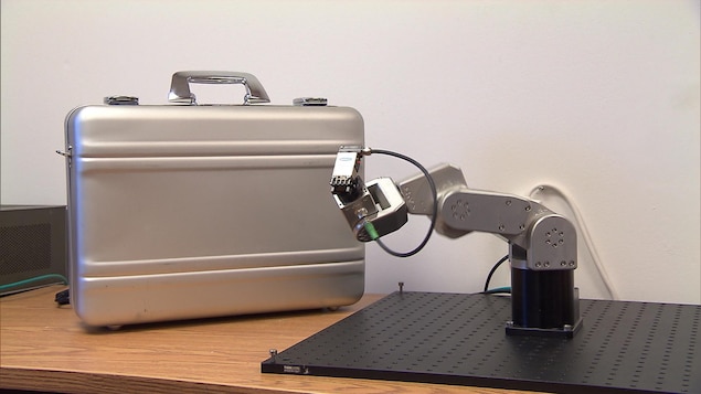 Le petit bras robotisé de Mecademic à côté d'un bagage de cabine Le petit bras robotisé de Mecademic à côté d'un bagage de cabine
