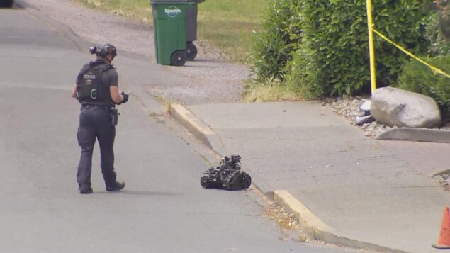 Un policier tient une télécommande avec laquelle il guide un petit robot.