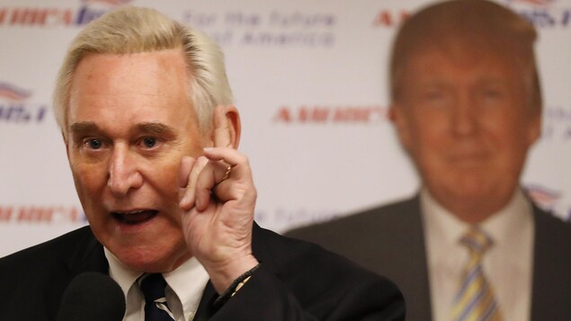 Plan rapproché de M. Stone, devant une affiche de Donald Trump. Plan rapproché de M. Stone, devant une affiche de Donald Trump.