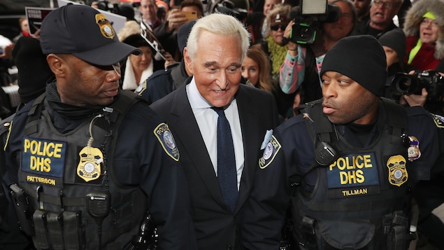 Roger Stone, en complet, est escorté par deux agents armés du département de la Sécurité intérieure.