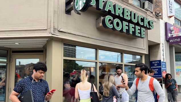 People crowd around a Toronto Starbucks to use its free wifi on the Bell network Friday morning during a major outage of Rogers Communications' mobile and internet networks that was causing widespread disruptions across Canada.