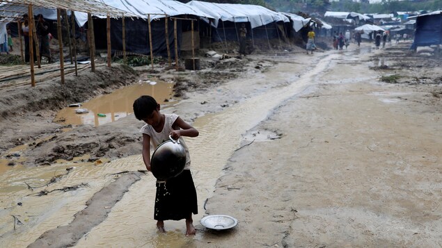 Un enfant dans un camp de réfugiés Rohingyas, une communauté musulmane persécutée au Myanmar, lave un plat avec l'eau d'un ruisseau qui s'est formé dans le sol. Un enfant dans un camp de réfugiés Rohingyas, une communauté musulmane persécutée au Myanmar, lave un plat avec l'eau d'un ruisseau qui s'est formé dans le sol.